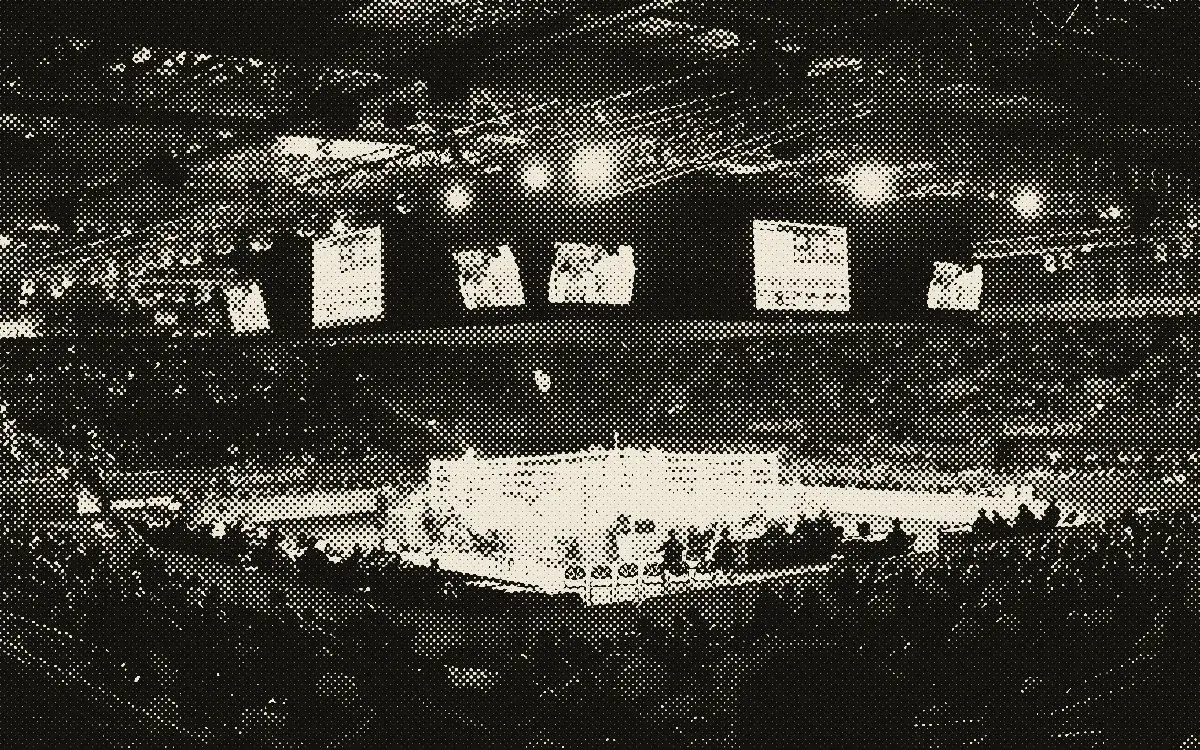 Grande salle de boxe avec un ring éclairé au centre et le public dans les gradins